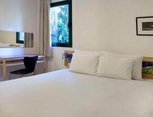 
a hotel room with a bed, desk, and window at Diaghilev LOFT live art hotel in Tel Aviv

