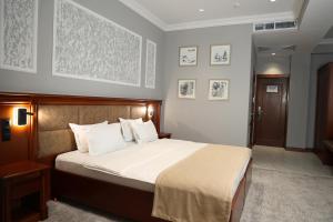 a bedroom with a large bed with white sheets at Mir Luxe Plaza in Tashkent