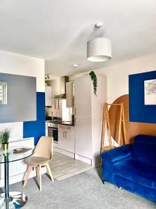 a living room with a blue couch and a kitchen at 1 Bed House at Velvet Serviced Accommodation Swansea with Free Parking & WiFi - SA1 in Swansea