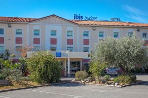 a hotel with a parking lot in front of it at Ibis Budget Fréjus Capitou in Fréjus