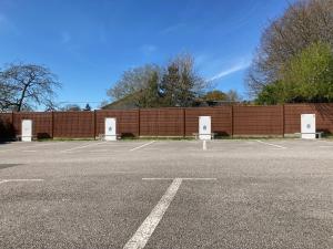 an empty parking lot next to a brick wall at The Originals City, Hôtel Le Boeuf Rouge, Saint-Junien in Saint-Junien