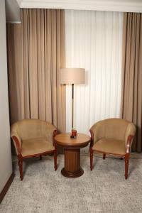 two chairs and a table and a lamp in a hotel room at Mir Luxe Plaza in Tashkent