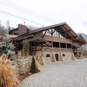 a large wooden building with a stone wall at BRB Park Hotel in Vizhenka