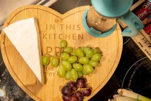 a wooden heart shaped cutting board with grapes on it at 1 Bed House at Velvet Serviced Accommodation Swansea with Free Parking & WiFi - SA1 in Swansea