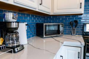 a kitchen counter with a microwave and blue tiles at The Harperwood's Haven in Harper Woods