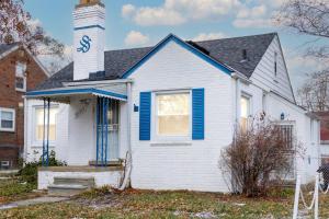 a white house with blue shutters and a clock tower at The Harperwood's Haven in Harper Woods