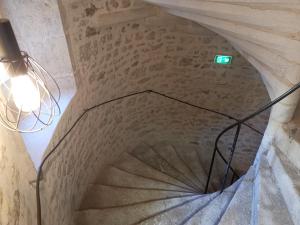 a spiral staircase in a castle with a green sign on it at Le Relais du Chapeau Rouge in Saint Loup Lamaire