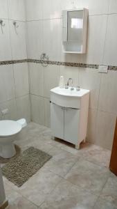 a white bathroom with a sink and a toilet at Los Cerezos de Ema in Puerto Iguazú