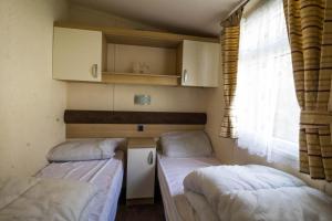 two beds in a small room with a window at Brilliant 8 Berth Caravan At Haven Caister Holiday Park In Norfolk Ref 30024d in Great Yarmouth