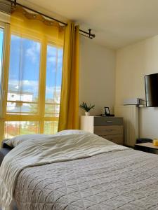 - une chambre avec un lit et une grande fenêtre dans l'établissement Cosy Yellow - Disney 15min walk - JO 30 min- Free Parking, à Serris