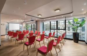 a conference room with a table and red chairs at Leonardo Hotel Bucharest City Center in Bucharest