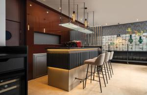 a bar in a restaurant with stools at a counter at Leonardo Hotel Bucharest City Center in Bucharest
