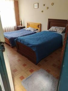 two beds in a bedroom with blue sheets at Casa con piscina para descanso in Chachagüí