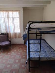 Zimmer mit 2 Etagenbetten und einem Stuhl in der Unterkunft Casa con piscina para descanso in Chachagüí