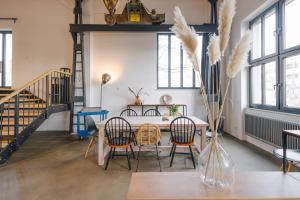 a dining room with a table and chairs and windows at ElbQuartier Apartments Magdeburg 'Fabrik61' in Magdeburg