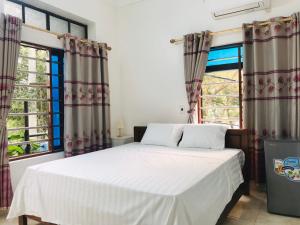 a bedroom with a bed and two windows at Tam Coc Sunset Homestay in Ninh Binh