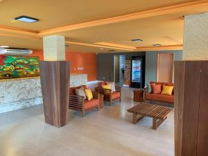 a lobby with couches and tables in a building at Pousada Amada Terra in Porto De Galinhas