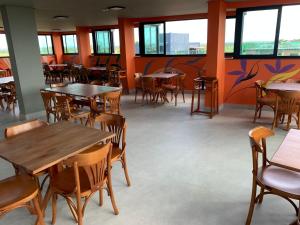 um restaurante com mesas, cadeiras e janelas em Pousada Amada Terra em Porto de Galinhas