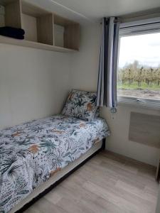 um pequeno quarto com uma cama e uma janela em Vakantiechalet Jonagold 4 personen em Hengstdijk