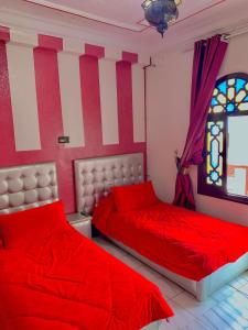 Hotel Sevilla في شفشاون: سريرين في غرفة نوم مع ملاءات حمراء ونافذة