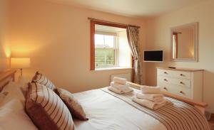 Un dormitorio con una cama blanca con toallas. en Nisbet's Tower, en Eyemouth