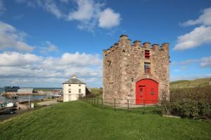 an old castle with a red door on a hill at Nisbet's Tower in Eyemouth