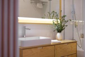a bathroom with a sink and a vase with flowers at Entre Ruas Apartments in Coimbra