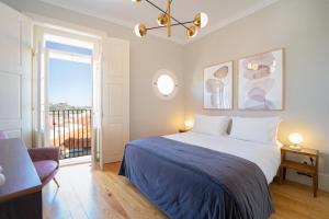 a bedroom with a large bed and a balcony at Entre Ruas Apartments in Coimbra
