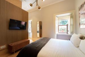 een slaapkamer met een bed en een tv aan de muur bij Entre Ruas Apartments in Coimbra