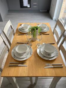 a wooden table with plates and wine glasses on it at 2 Bedroom City Centre Apartment in Hemel Hempstead in Hemel Hempstead