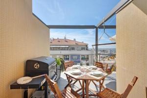 - un balcon avec un grill, une table et des chaises dans l'établissement Cantinho da Praia da Barra, à Gafanha da Nazaré