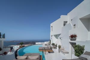 Cette chambre offre une vue sur un bâtiment blanc doté d'une piscine. dans l'établissement Akra Suites & Spa, à Imerovigli