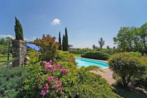 a swimming pool in a garden with flowers at VILLA LE DUE LUNE 6 PAX , SWIMMING POOL, WI FI, TUSCAN STYLE in Filattiera