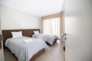 una camera d'albergo con due letti e una finestra di Meirinha House a Viana do Castelo