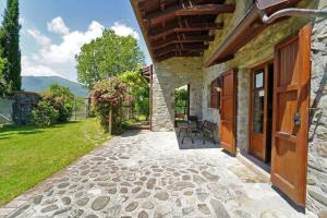 a stone house with a patio and a yard at VILLA LE DUE LUNE 6 PAX , SWIMMING POOL, WI FI, TUSCAN STYLE in Filattiera