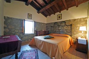 ein Schlafzimmer mit einem Bett und einer Steinmauer in der Unterkunft Villa Le Due Lune with Pool by VILLASRETREATS in Filattiera