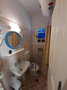 uma casa de banho com um lavatório, um WC e um espelho. em Pension Selenti em Tinos