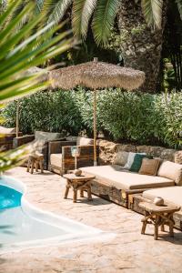 a patio with a couch and an umbrella next to a pool at Hotel Can Sastre in Santa Gertrudis de Fruitera