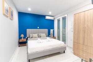 een slaapkamer met een blauwe accentmuur en een bed bij elegant escapes 2 nea smyrni in Athene