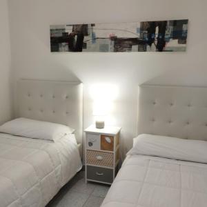 a bedroom with two beds and a night stand with a lamp at Guest House Oleandro IUN 2727 in Santa Maria Navarrese