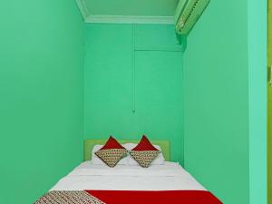 a bedroom with a bed with two red pillows at OYO 92496 Faraas Homestay Syariah in Nongsa