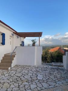 a white house with a stone patio and stairs at Akritochori house with great view in Akritokhórion