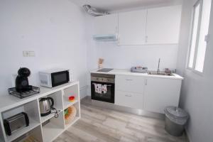 eine weiße Küche mit einem Herd und einer Mikrowelle in der Unterkunft COVESA III Centro Levante Beach in Benidorm