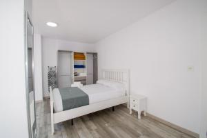 ein kleines weißes Schlafzimmer mit einem Bett und einem Spiegel in der Unterkunft COVESA III Centro Levante Beach in Benidorm