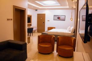 ポートハーコートにあるMoratel Hotelsのベッド1台と椅子2脚が備わるホテルルームです。