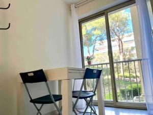 a table and two chairs in front of a window at Studio résidence de Standing Piscine proche plage in Antibes