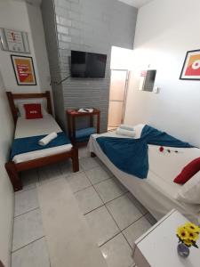 a small room with two beds and a tv at Pousada Torre dos Mouros in Pirenópolis