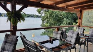 a table and chairs on a porch with a view of a lake at Hotel Zátoka in Senec