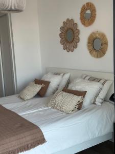 białe łóżko z poduszkami i lustrami na ścianie w obiekcie Prachtig appartement met zeezicht in Estepona Costa del Sol w mieście Estepona