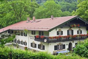 uma casa branca com flores vermelhas na varanda em Pension Brucker em Aschau im Chiemgau